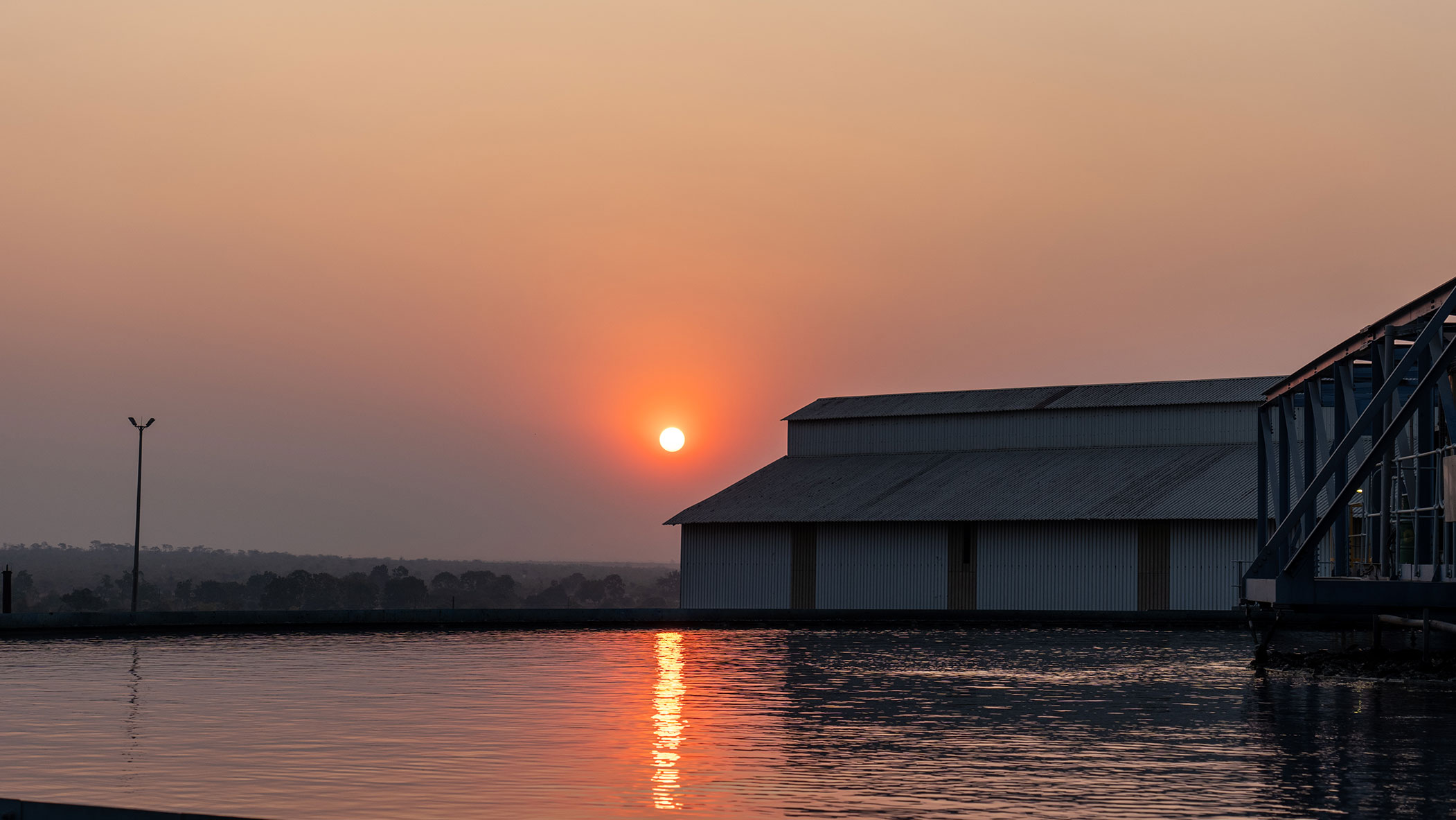 Sunset view over International Resources Holding’s Mopani Copper Mines facility with reflection on the water reservoir
