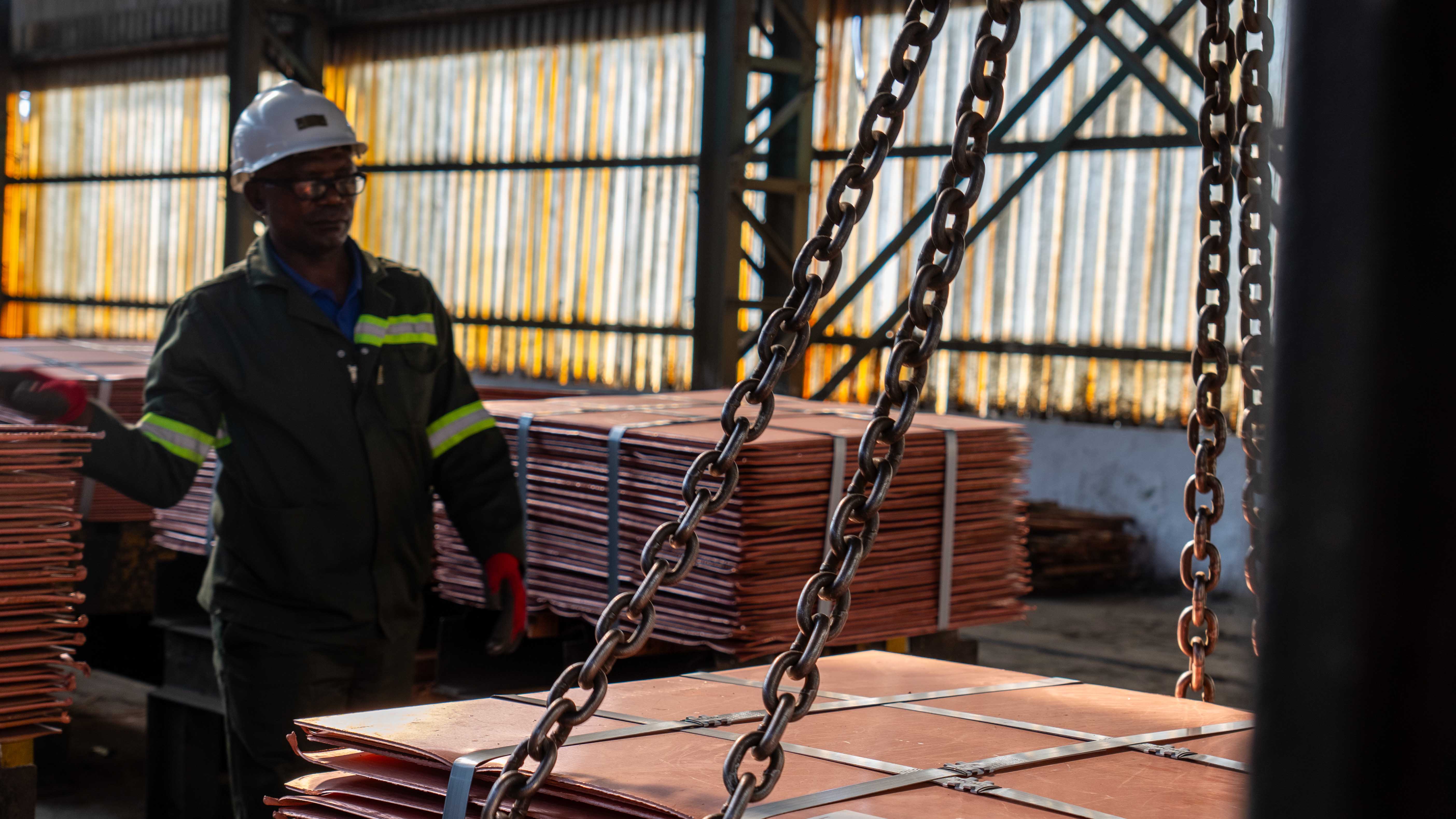 IRH worker overseeing lifting of copper cathode sheets inside Mopani Copper Mines warehouse